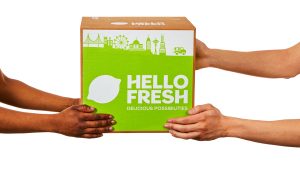 Four hands holding a HelloFresh Meal Kit Delivery Box