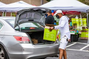 Man loading a HelloFresh Meals with Meaning box into the trunk of his car