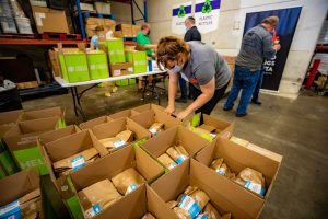 Woman prepping HelloFresh Meals with Meaning food boxes in a warehouse